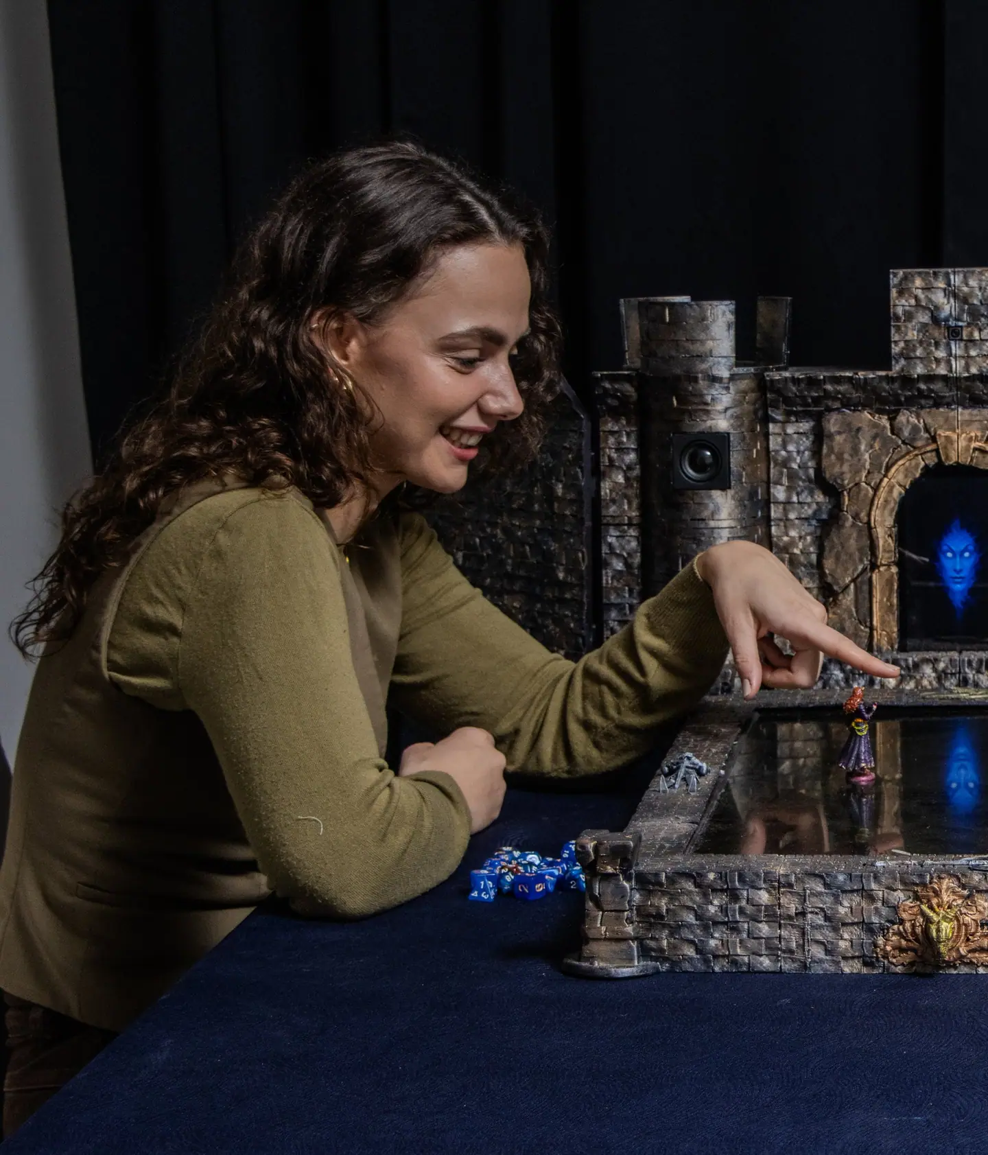 A player laughs and points at a miniature on the Doungim map board, in front of the glowing gate