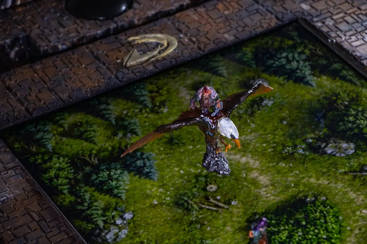 Eine geflügelte Miniatur auf einer Waldkarte auf dem Doungim Brett, neben dem Doungim Logo